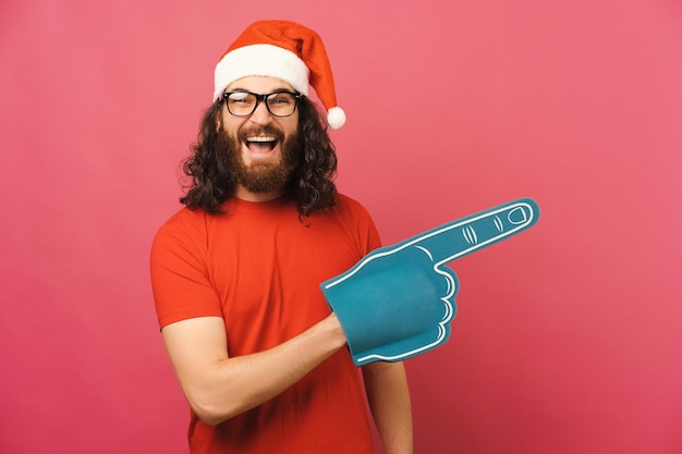 Excited long haired bearded man indicates direction with a blue foam fan glove