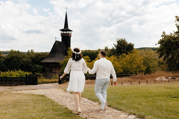 興奮した可愛い若いカップル2人の友人家族の男性白い服を着た女性手をつないで走る歩く散歩する夏の日に屋外で一緒に踊る結婚