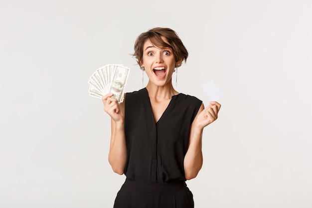 Excited lucky woman showing credit card and money