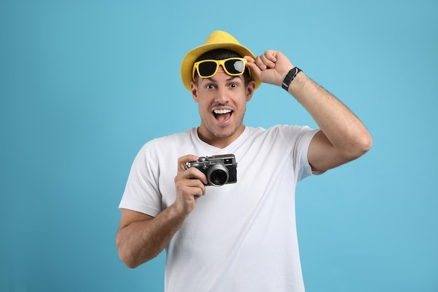Excited male tourist with camera on turquoise background