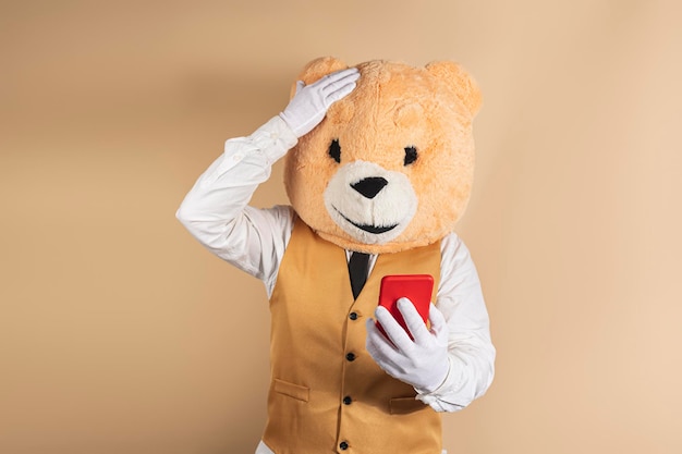 Excited man in bear mask reading good news on mobile phone on a yellow background