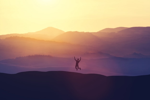 Excited man jumping of joy on a hill.