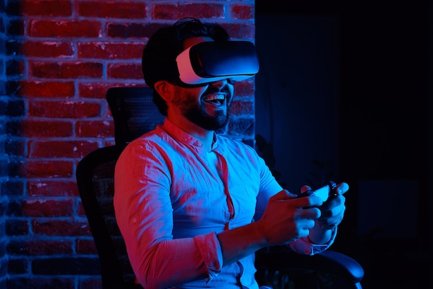 의자에 앉아 vr 안경을 쓰고 게임을 하는 동안 웃고 있는 흥분된 남자