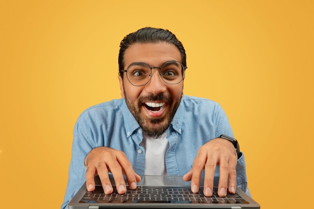 Excited man using laptop over desk