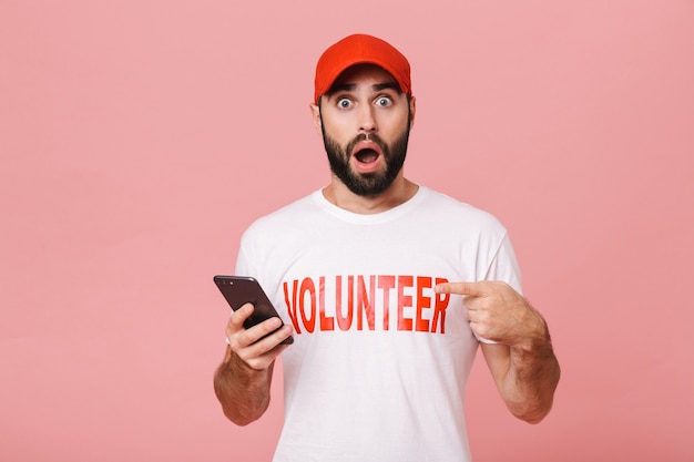 excited man volunteer wearing uniform t-shirt wondering and holding cellphone isolated