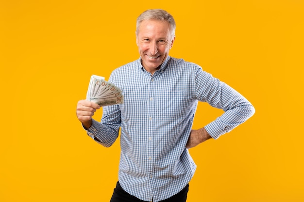 Excited mature man holding a lot of money cash