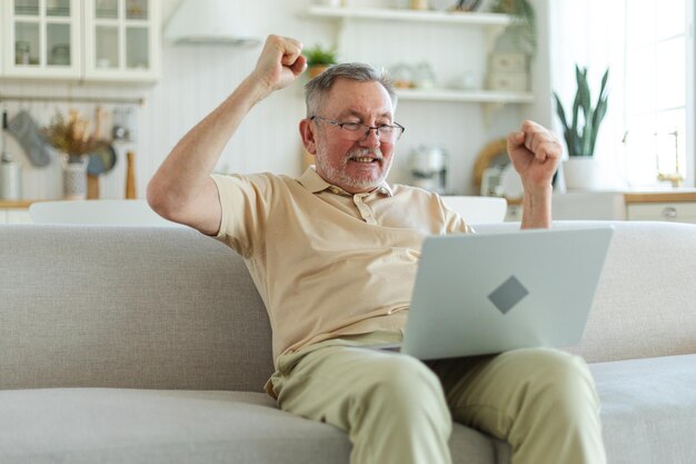 Photo excited middle aged senior man euphoric winner older mature grandfather looking at laptop reading