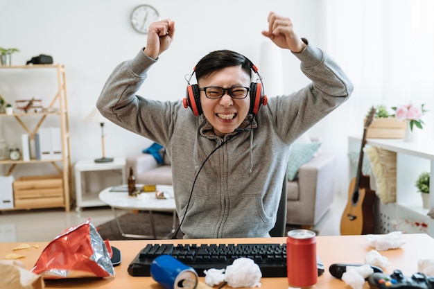 Asian Young Girl Friend Angry At Boyfriend Playing Online Game On Computer.  Mad Female Pushing Guy And Scolding At Him. Frowning Man Ignores His  Annoyed Lover And Wearing Headphones Keep Having Fun.