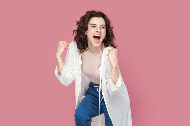 Excited overjoyed woman outfit clenched her fists celebrating victory expressing happiness