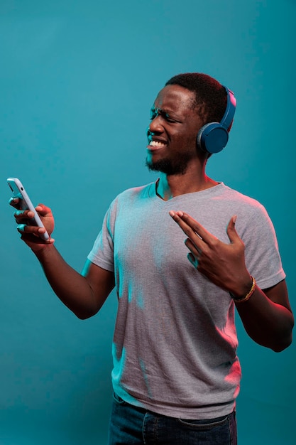 Excited person listening to music on headset and using phone,\
enjoying radio sound from smartphone. young model holding modern\
gadget and wearing headphones to hear mp3 record song.