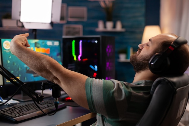 Giocatore entusiasta che vince un'importante competizione di esport online di sparatutto spaziale che gioca su un computer potente. videogiochi in streaming per giocatori professionisti professionisti utilizzando microfono e cuffie professionali