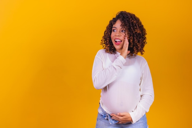 Excited pregnant woman telling the news with hand on open mouth
