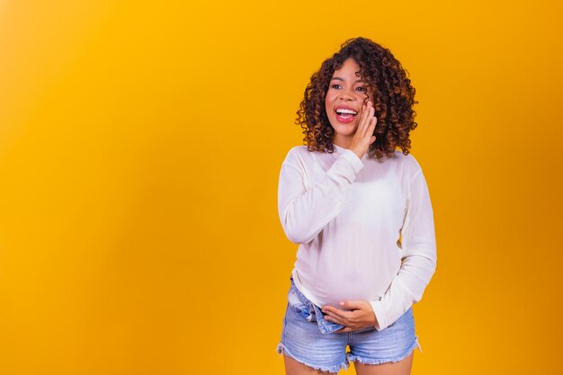 Excited pregnant woman telling the news with hand on open mouth