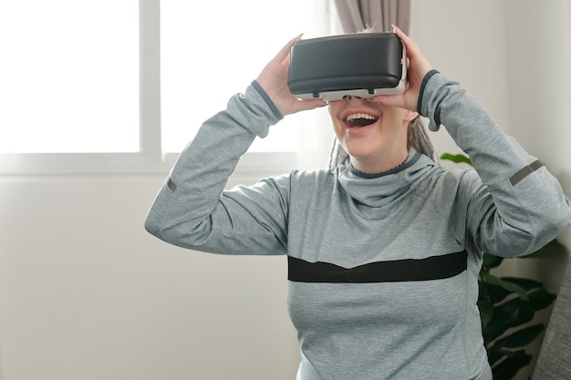 Excited pregnant young woman trying to play videogame in virtual reality headset for the first time