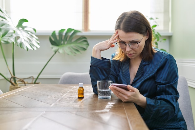 Excited sad mature woman reading smartphone