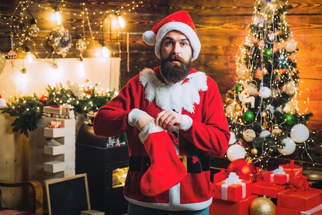 Excited santa man posing on vintage wooden background surprised santa christmas gift