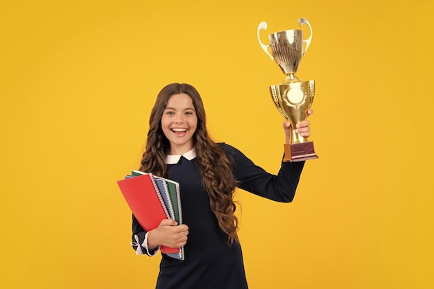 Excited schoolgirl  school uniform celebrating victory with trophy Teen holding winning award prize