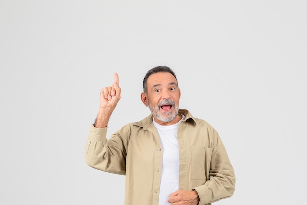 Excited senior pointing upwards on white background