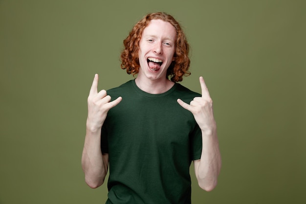 excited showing goat gesture young handsome guy wearing green t shirt isolated on green background