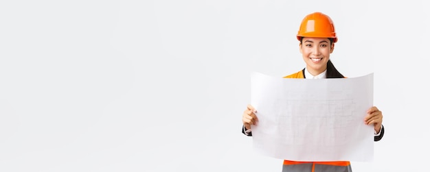 Excited smiling asian female engineer at construction area study blueprints looking pleased while re