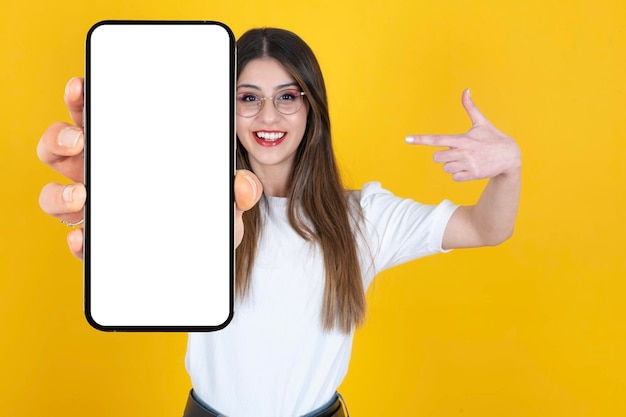 Excited smiling caucasian woman demonstrating big smartphone with empty blank screen mockup