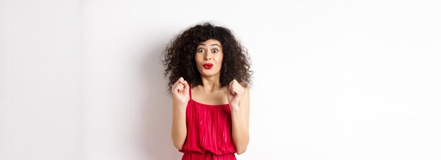 Foto donna sorridente eccitata desiderosa di provare qualcosa saltando da divertimento e sorridendo indossando un vestito rosso