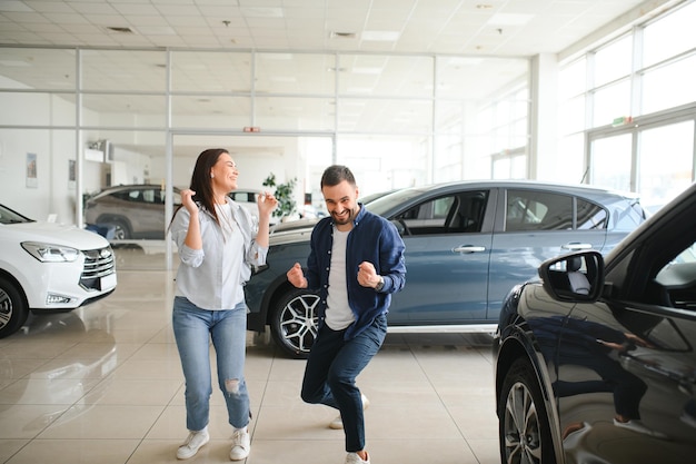 Photo excited spouses dancing in dealership office after buying new car