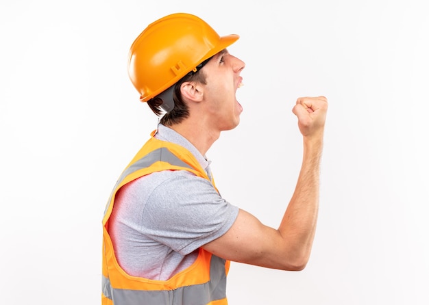 Excited standing in profile view young builder man in uniform showing yes gesture 