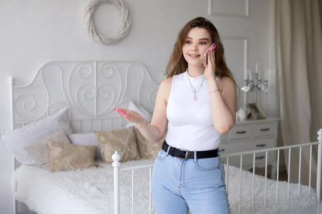 An excited successful european woman with a phone raises her\
hands a remote worker in her apartment