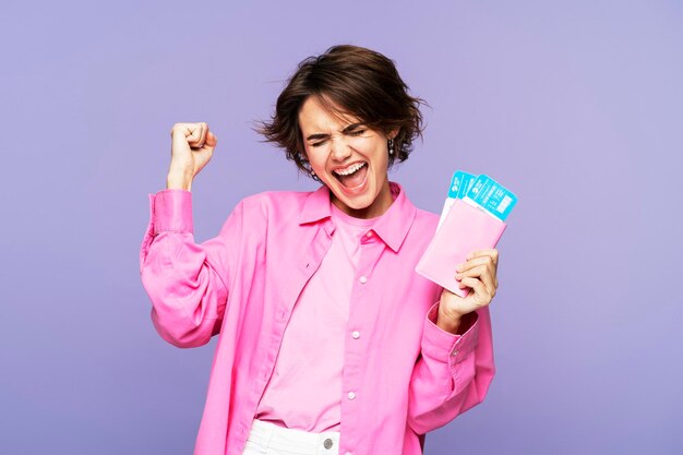 Excited teen woman screaming rejoicing with a passport and airplane ticket