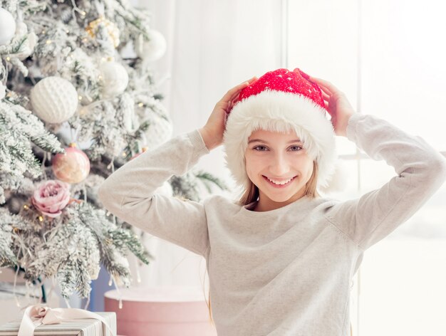 クリスマスツリーの近くの興奮の10代の少女