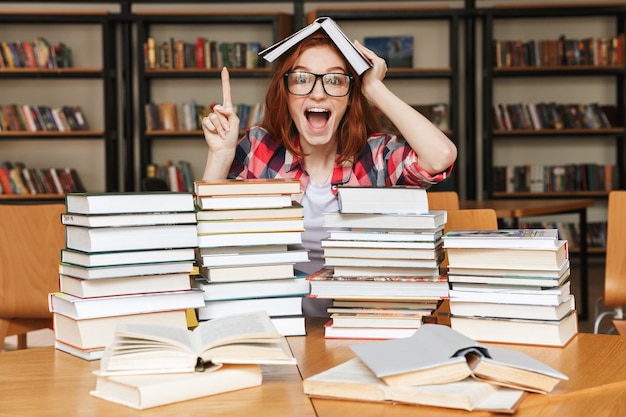 Excited teenage girl sitting at the library table