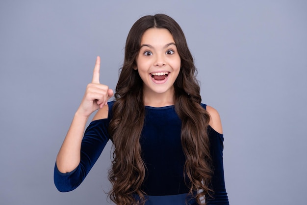 Excited teenager girl Portrait of cute teenager pointing up with finger Girl has great new idea Successful child