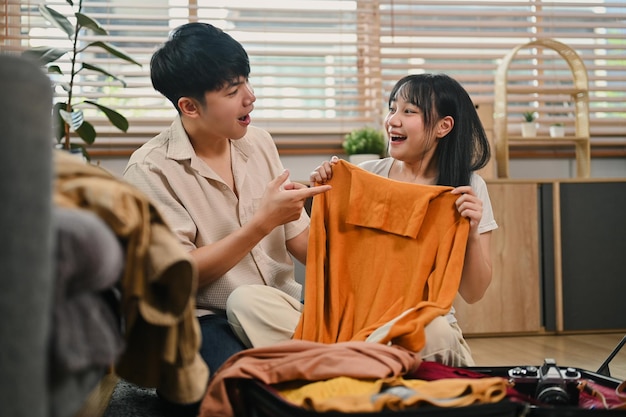 Excited tourists couple packing cloth and stuff for vacation trip in the living room at home