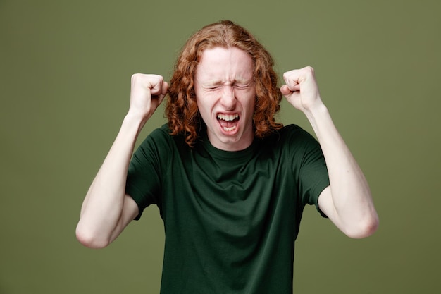 Excited with closed eyes young handsome guy wearing green t shirt isolated on green background