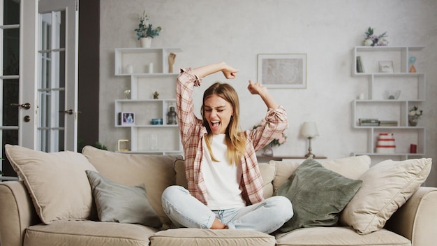 excited woman celebrating success on sofa at home