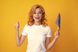 Взволнованная женщина с флагом европейского союза, изолированная от желтой ассоциации ес счастливая девушка с флагом иммиграции европейского союза и путешествия по европе