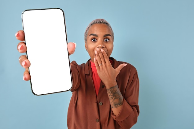 興奮した女性がスマートフォンを握り青い背景に白い画面を掲げています