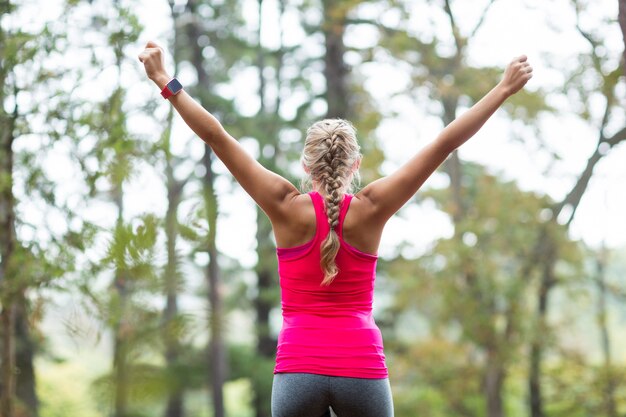 Excited woman standing in forest