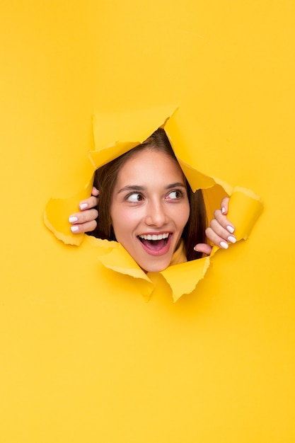 Excited woman through torn paper hole