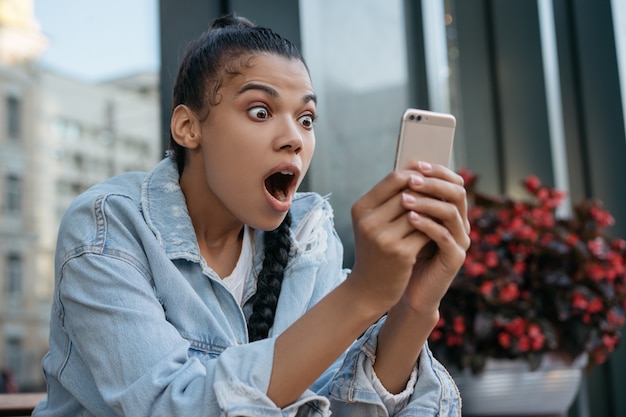 Excited woman using mobile phone, reading breaking news, watching movie