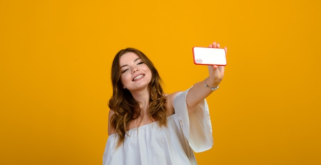 Excited woman with digital device. Studio shot of girl holding smartphone