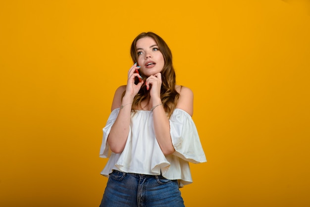 Excited woman with digital device. Studio shot of shocked girl holding smartphone, emotional