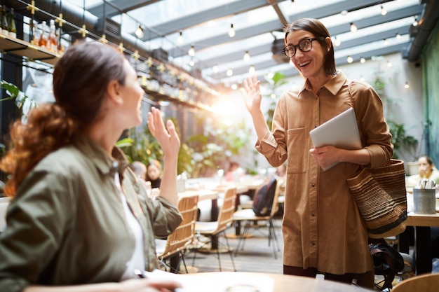 Excited women greeting each other in cafe