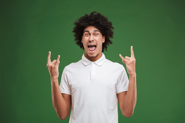 Excited young african curly man make rock gesture.