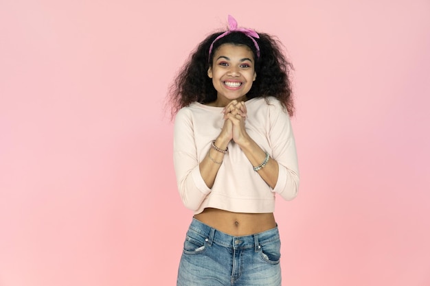 Excited young african girl look at camera isolated on pink studio background