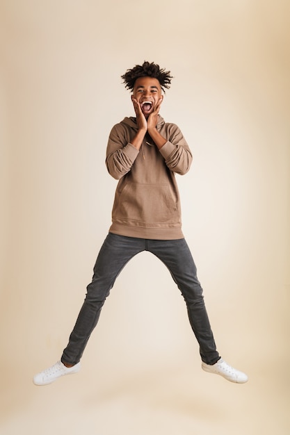 Excited young afro american man dressed in hoodie jumping isolated