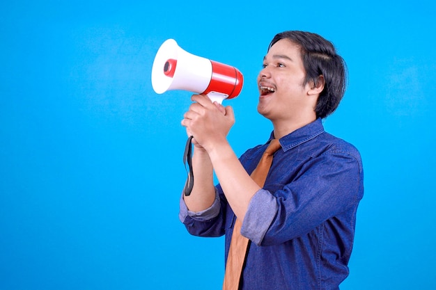 Excited young Asian business guy making announcement with megaphone in hands