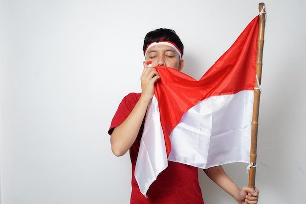 Foto eccitato giovane asiatico che tiene bandiera indonesiana mentre celebra il giorno dell'indipendenza dell'indonesia