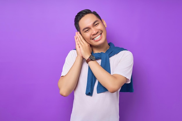 Excited young Asian man wearing white tshirt put his hand on his cheek isolated over purple background people lifestyle concept